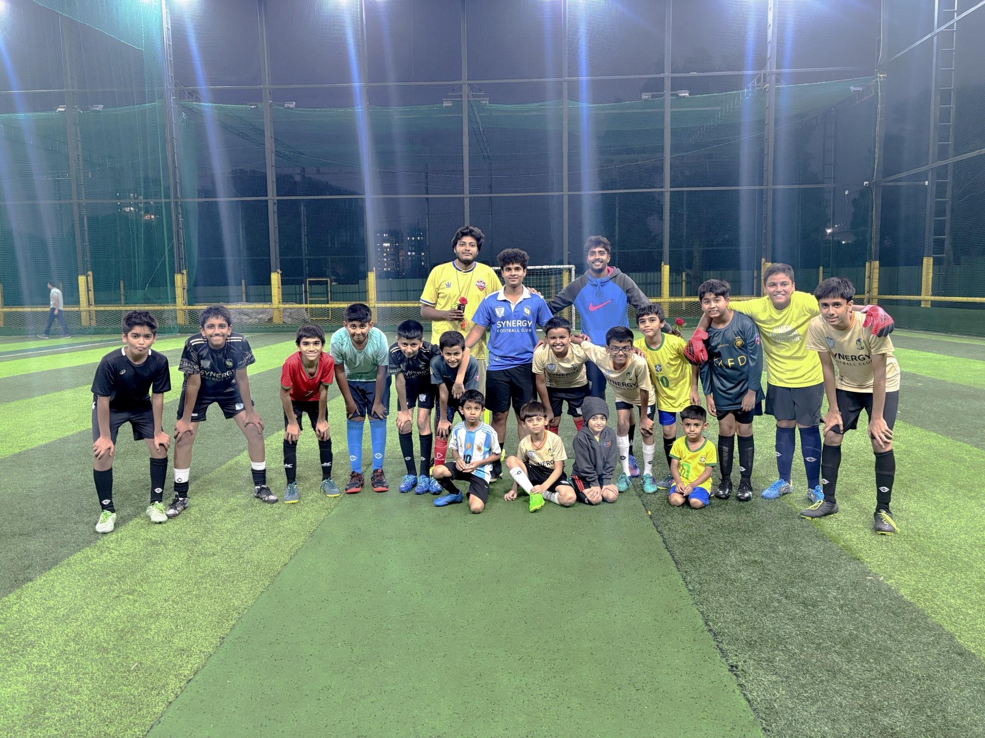 Synergy FC players and coaches together on the floodlit turf